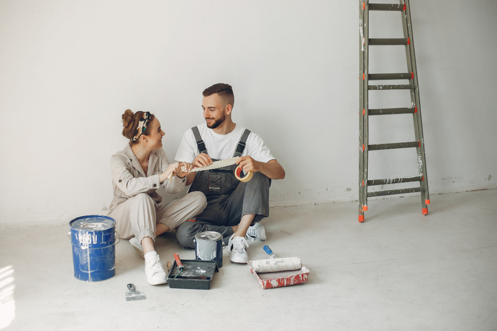 couple assis par terre font des travaux dans leur futur maison